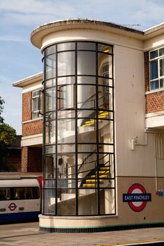 a bus parked in front of a building with a spiral staircase on the side of it