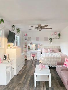 a bedroom with white furniture and pink accessories on the bed, dressers, tv, and ceiling fan