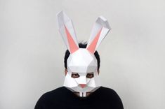 a man wearing a paper bunny mask and black shirt with his head in the shape of a rabbit