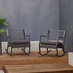 two rocking chairs sitting on top of a wooden floor next to a potted plant