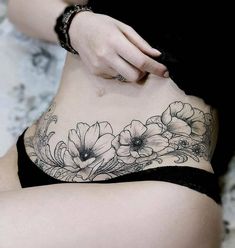 a woman is showing off her stomach with flowers tattooed on it's side belly