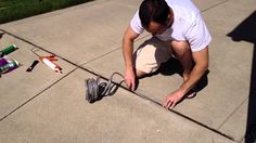 a man kneeling down on the ground working on an electrical wire with tools around him