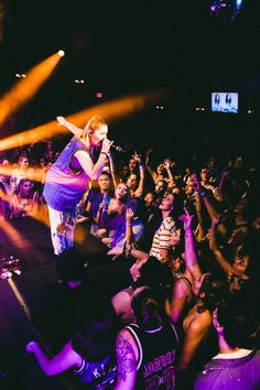 a woman standing on top of a stage in front of a crowd