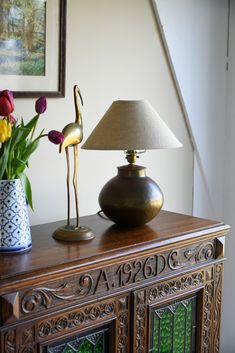 a lamp on top of a table next to a vase with tulips in it