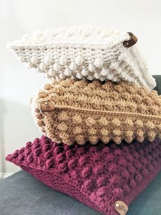 three crocheted pillows stacked on top of each other in different colors and sizes