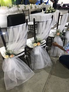 the chairs are decorated with white tulle and flowers