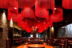 a restaurant with red lights hanging from the ceiling and wooden tables in front of them