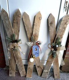 three wooden skis decorated with christmas decorations and bows on the side of a door