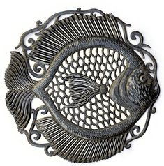 a metal fish wall hanging on the side of a white wall with an intricate design