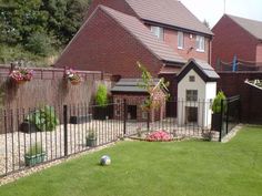 a fenced in backyard area with flowers and potted plants on the grass next to it