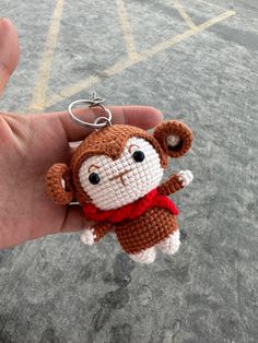 a hand holding a small crocheted monkey keychain