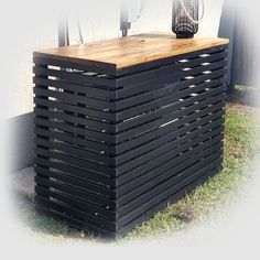 a wooden table sitting in the grass next to a fence with a vase on top