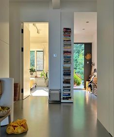 a living room filled with furniture and a tall book shelf next to a doorway covered in books