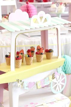 an ice cream stand with strawberries and raspberries in cones on the table