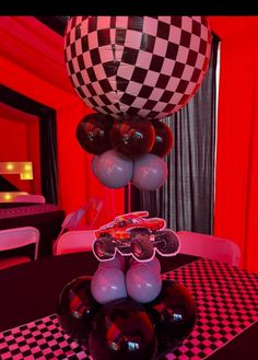 a table topped with balloons in the shape of cars and checkerboard pattern on it