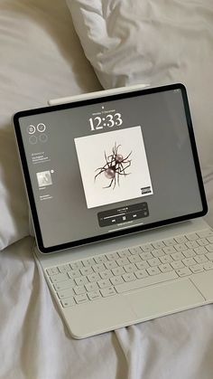 an open laptop computer sitting on top of a bed with white sheets and pillows in the background