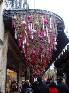 people are walking down the street in front of shops with ornaments hanging from the ceiling