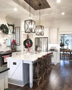 a large kitchen with white cabinets and wooden flooring, decorated for christmas or new year's eve