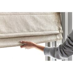 a woman is pulling up the curtains with her hand