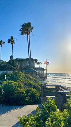 the sun shines brightly in front of some houses and palm trees at the beach