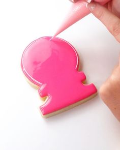 a person is decorating a cookie with pink icing