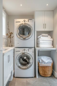 a washer and dryer are stacked in a laundry room with white cabinetry