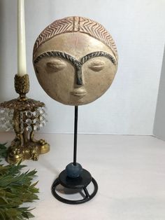 a decorative head on a stand next to a candle