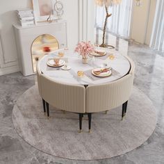 a round table with two chairs and plates on it in the middle of a room