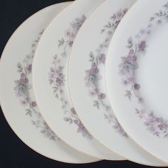 five plates with purple flowers on them are lined up in a row and one is empty