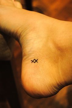 a person with a small cross tattoo on their left foot and the word love written in black ink