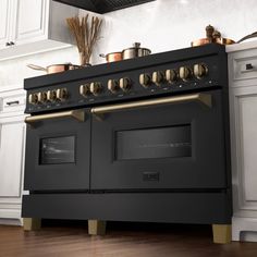 a black stove top oven sitting inside of a kitchen next to white cabinets and wooden floors