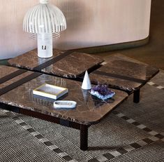 a marble coffee table sitting on top of a checkered rug next to a lamp