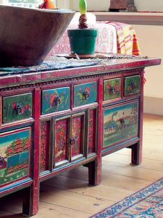 an old dresser with painted drawers and a bowl on top