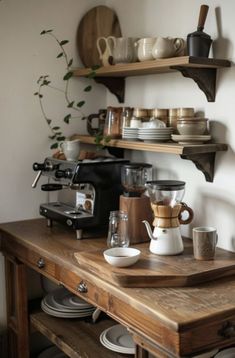 a wooden table topped with lots of plates and cups next to a wall mounted coffee maker