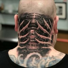 the back of a man's head with black and grey tattoos on his neck