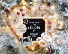 a baby announcement surrounded by christmas decorations and other holiday items, including a photo frame with the words i'll be home for christmas written on it