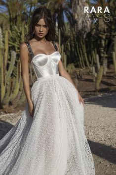 a woman in a white dress standing next to cacti and cactus trees with the caption rara avs