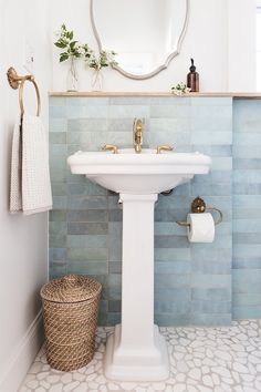 a white pedestal sink sitting under a mirror in a bathroom next to a toilet paper roll