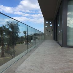 a balcony with glass railing and palm trees