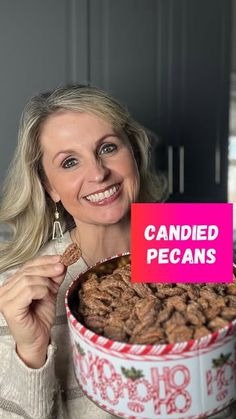 a woman holding up a sign that says candied pecans in front of her