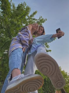 two people standing on top of each other with their feet in the air and one person holding a cell phone