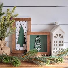 some christmas decorations are sitting on a shelf next to a small house and fir tree