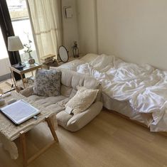 an unmade bed sitting on top of a hard wood floor next to a window