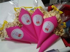 three pink cones filled with popcorn sitting on top of a table