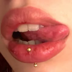 a woman's lips with gold piercings on her nose and lip ring in front of her mouth