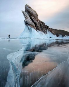 an iceberg is reflected in the water on a cloudy day