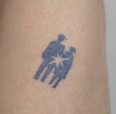 a small tattoo on the back of a person's arm that has an image of two people holding each other