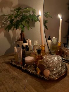 candles, bottles and soaps are arranged on a tray in front of a mirror