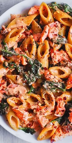 a white bowl filled with pasta and meat covered in sauce on top of a wooden table