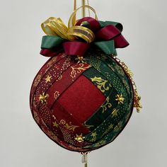 a christmas ornament hanging on a pole with ribbon and bow around the top